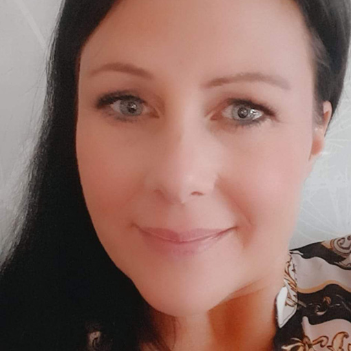 En kvinna med mörkt hår ler och tittar mot kameran.