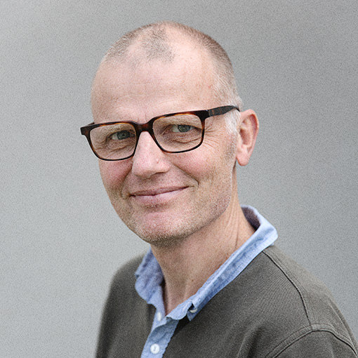 En man med glasögon ler mot kameran.
